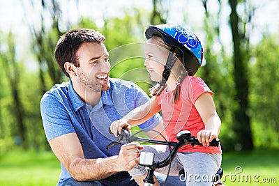 Girl learning to ride a bike with her father Stock Photo