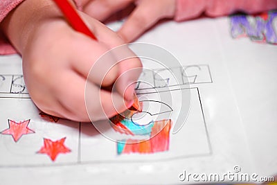 A girl learns to count, a girl colors a number five with a pencil. Stock Photo