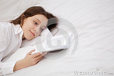 Teenage girl lying near the book on the bed in her dreams of the good Stock Photo