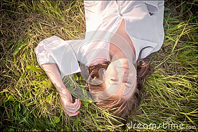 The girl lies on the grass. Happy smiling beautiful girl lying among grass and flowers. on a blue background Stock Photo