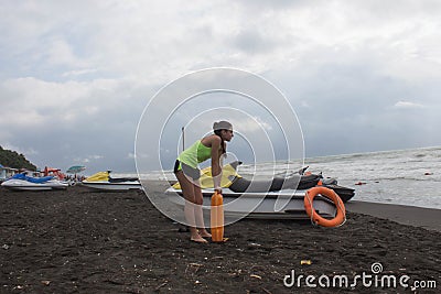 Girl lifeguard on duty keeping a buoy at the beach. Water scooter, Lifeguard rescue equipment orange preserver tool on beach. Saf Stock Photo