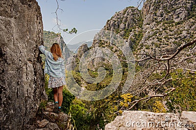 Girl in the light dress standing place a hand on the rock Editorial Stock Photo