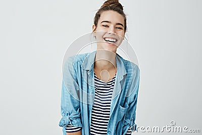 Girl likes funny jokes. Smart good-looking student with bun hairstyle trembling from laugh, smiling positively and being Stock Photo