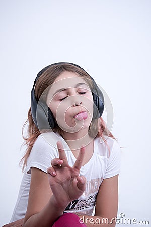 Girl listening a music on headphone Making a sign of peace and love Stock Photo