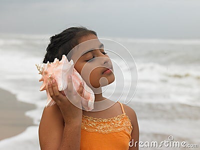 Girl listening to a conch Stock Photo