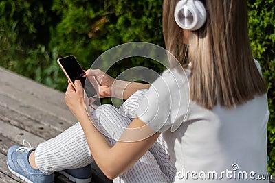 Melodies and Style: Girl in Striped Pants Enjoying Music and Technology in the Park Stock Photo