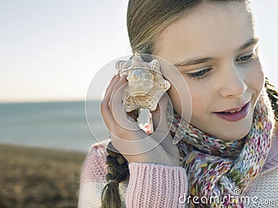Girl Listening To Seashell On Beach Stock Photo