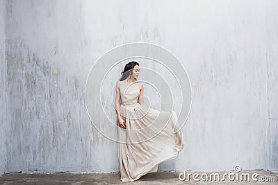 Girl with long black hair in a gentle silk wedding dress in pastel color Stock Photo