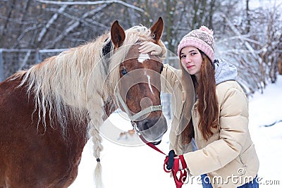 Girl with long brown hair and chestnut horse with plaited mane close up portrait on winter snowy background Stock Photo