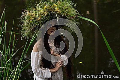 Girl in long dress and wreath is dipping into river Stock Photo