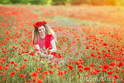 A girl in a red dress weaves wreaths of poppy flowers in a poppy field. Stock Photo