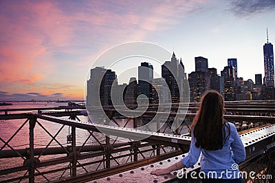 Girl look at Manhattan buildings from Brooklin Bridge at dawn Stock Photo