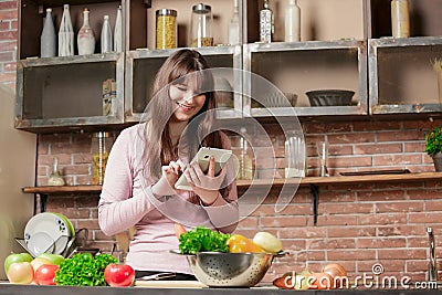 Girl look at the tablet.Young Woman Cooking in the kitchen at home. Healthy Food. Stock Photo