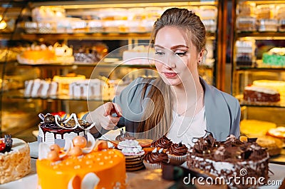 Girl looking at the bakery window with different pieces of cakes. Stock Photo