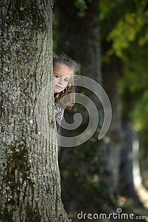 Girl looking from behind a tree Stock Photo