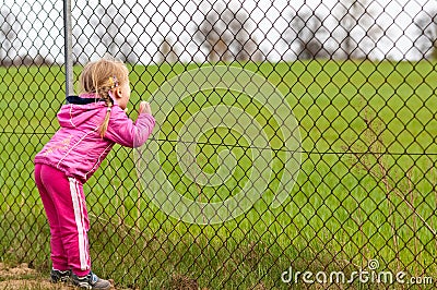 Girl looking through fence Stock Photo