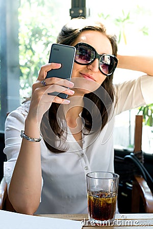 Girl looking at her smartphone and taking a selfie with glasses - telecommunication advertising Stock Photo