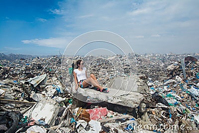 Girl looking a side among mountains of trash at garbage dump Stock Photo