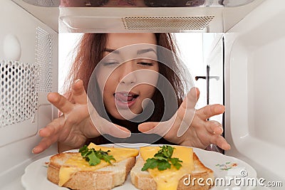Girl looks in a microwave Stock Photo