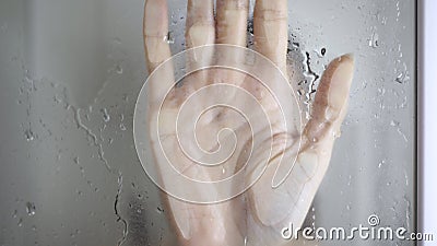 Girl loses consciousness in bathroom. Female hand on blurry glass of shower door Stock Photo