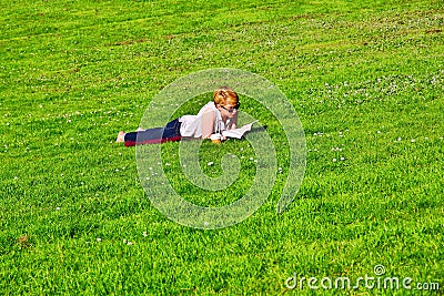 Girl lying on grass and reading Editorial Stock Photo