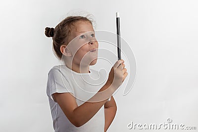 Girl magician holding up a magic wand - young magician performing with a magic wand - side view against white background Stock Photo