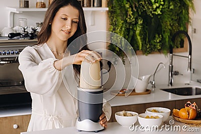 a girl makes a cocktail in a fruit blender in the kitchen. Diet for weight loss Stock Photo