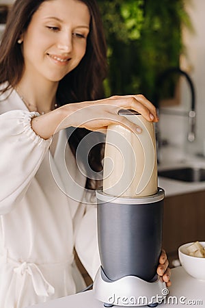 a girl makes a cocktail in a fruit blender in the kitchen. Diet for weight loss Stock Photo