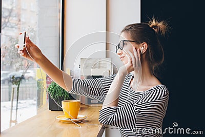 Girl makes selfie on smartphone in coffee shop Stock Photo