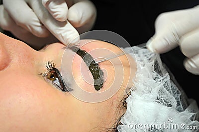 Girl with makeup lying on procedure of microblading. Cosmetologist makes permanent makeup on the eyebrows Stock Photo