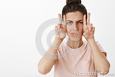 Girl making faces as feeling gloomy trying cheer up fooling around frowning and smirking showing peace gesture sideways Stock Photo