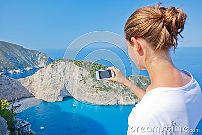 Girl making photo with Navagio bay and Ship Wreck beach in summer. The famous natural landmark of Zakynthos, Greek Stock Photo