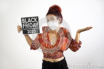 Girl with mask raising her hands and shoulders in show of resignation and conformity and holding a Black Friday 2020 poster with Stock Photo