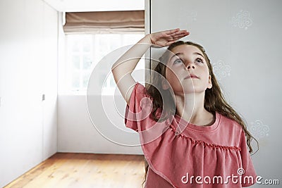 Girl Measuring Height Standing Against Wall At Home Stock Photo