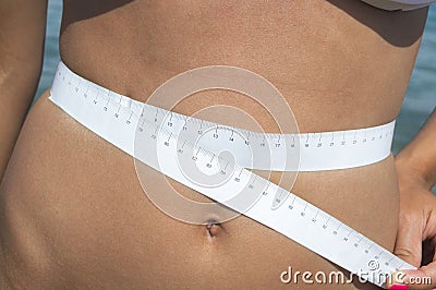 Girl measuring her waist at the seaside Stock Photo
