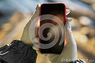 Girl medic in a mask and a protective suit stands in the clinic holds the phone in his hand Stock Photo