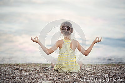 A girl meditating on the beach Stock Photo