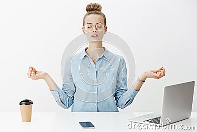 Girl meditating at work sitting in lotus pose with nirvana orbs near laptop and smartphone trying relax and get rid of Stock Photo