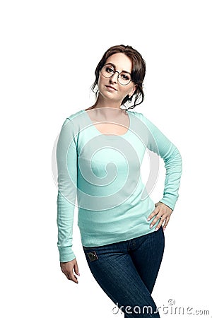 A girl in a mint-colored jumper, blue jeans and round glasses poses, looking into the camera, a hand on her hip. Stock Photo