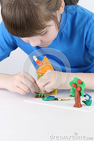 Girl molds house, tree, flowers from plasticine Stock Photo