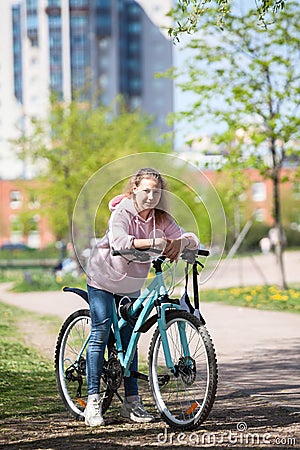 Girl on a mountain bike on urban street, beautiful portrait of a cyclist in sunny weather Stock Photo