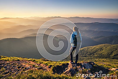 Girl on mountain peak looking at beautiful mountains at sunset Stock Photo