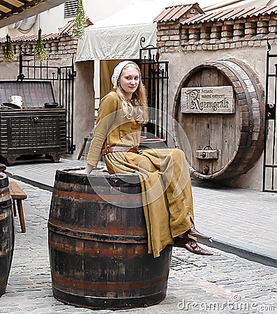 The girl in a national suit sits on a big barrel, advertizing be Editorial Stock Photo