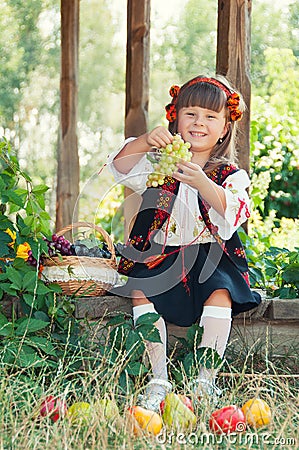 Girl in the national Ukrainian costume sitting in the garden with fruit Stock Photo