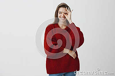 Girl never stops looking after her boyfriend. Confident joyful caucasian woman in loose red sweater, showing okay or Stock Photo