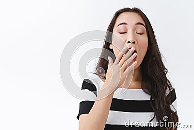 Girl is not morning person. Cute and silly young sleepy asian woman in striped t-shirt, yawning, cover opened mouth and Stock Photo