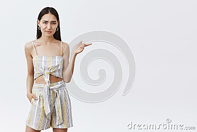 Girl not sure new model fits in squad. Portrait of unsure and doubtful displeased female in trendy outfit, pointing Stock Photo
