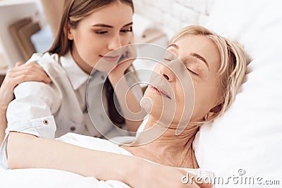 Girl is nursing elderly woman at home. Woman is sleeping peacefully. Stock Photo