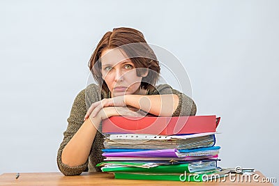 Girl office staff thoughtfully leaning on a stack of folders Stock Photo