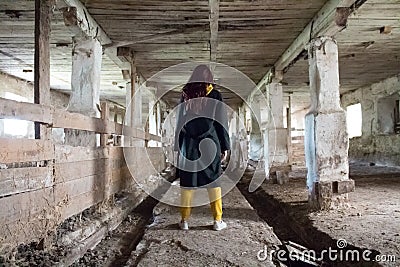 A girl in an old abandoned scary room like a barn or stable. An abandoned factory barn and stable where cows and horses Editorial Stock Photo